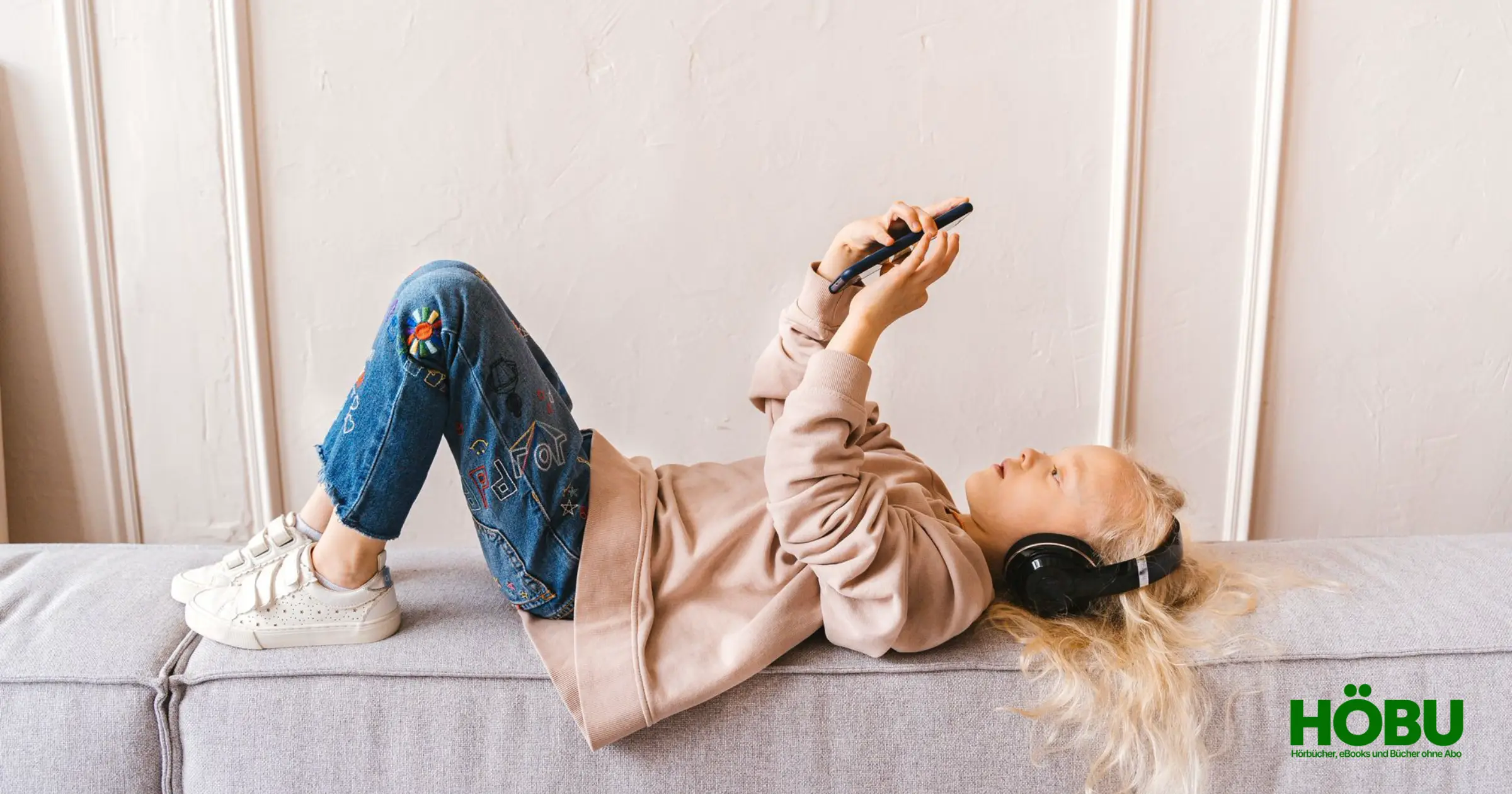 Mädchen liegt auf dem Sofa und hört ein Kinderhörspiel
